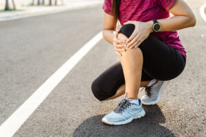 Female runner kneeling on track and holding her painful knee