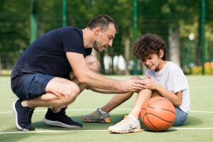 Basketball coach helping young athlete with knee trauma