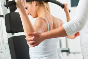 Physical therapist assisting female patient with arm exercises